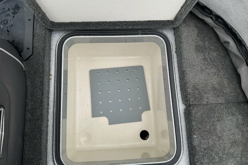 Slide: The Image of 2017 Ranger Z175 boat storage compartment with gray interior and drainage hole. - 17