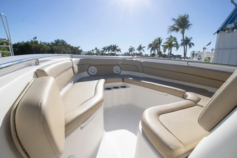 Slide: The Image of 2015 Tidewater 230 LXF boat interior with beige seating and sunny palm tree backdrop. - 10