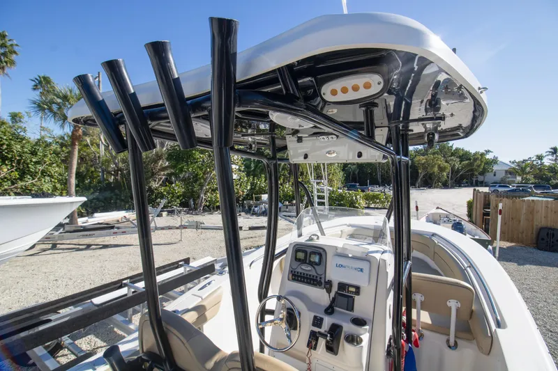 Slide: The Image of 2015 Tidewater 230 LXF boat interior with console and T-top, parked outdoors. - 13