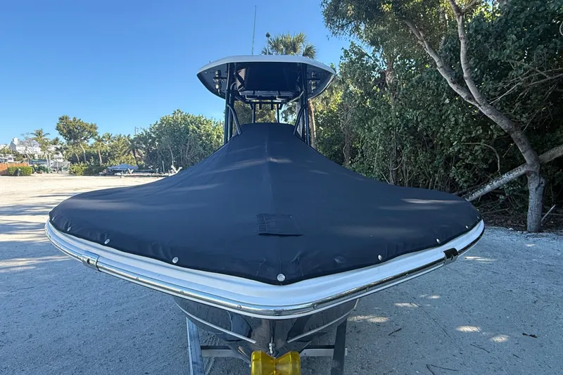 Slide: The Image of 2015 Tidewater 230 LXF boat with black cover, parked on sandy ground. - 3