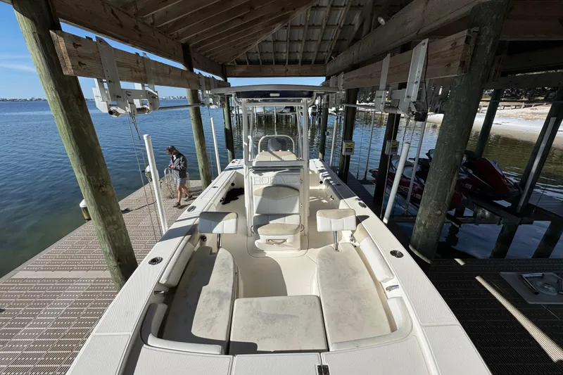 Slide: The Image of 2015 Robalo 246 Cayman boat docked under a wooden shelter by the water. - 15