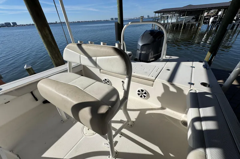 Slide: The Image of 2015 Robalo 246 Cayman boat interior with seating and outboard motor, docked by the water. - 19