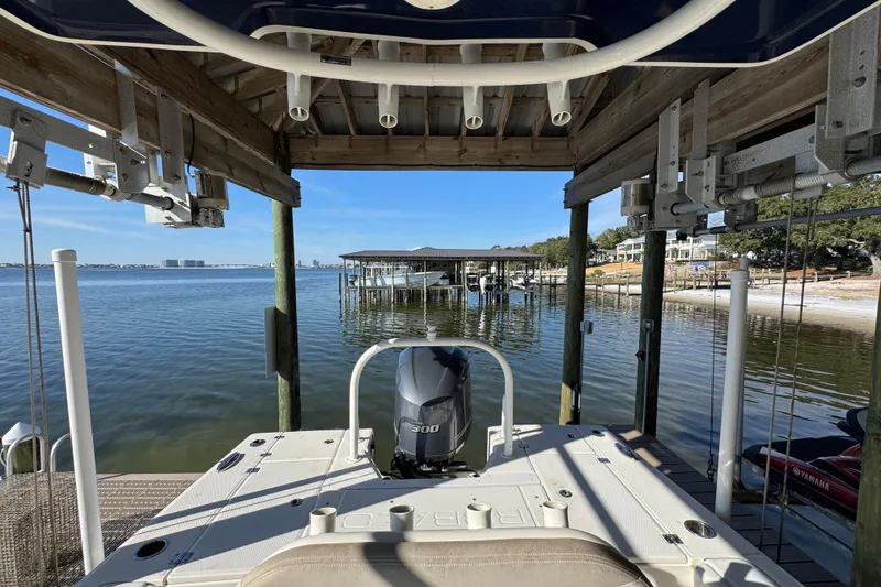 Slide: The Image of 2015 Robalo 246 Cayman boat docked by a serene waterfront with clear blue skies. - 21