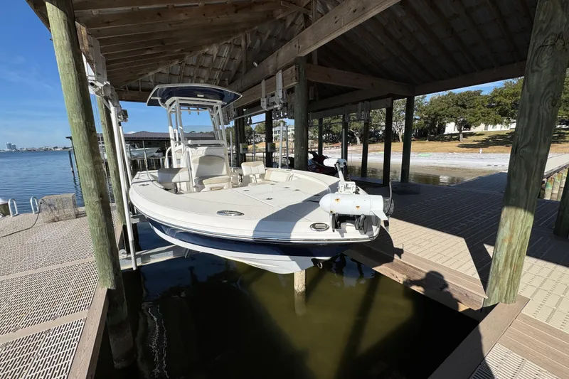 Slide: The Image of 2015 Robalo 246 Cayman boat docked under wooden shelter by the water. - 3