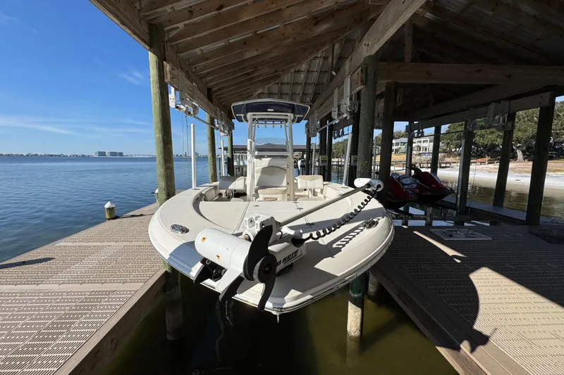 Slide: The Image of 2015 Robalo 246 Cayman boat docked under a wooden shelter by the water. - 4