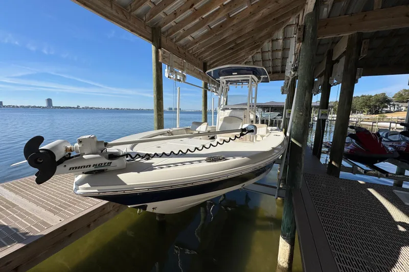 Slide: The Image of 2015 Robalo 246 Cayman boat docked under a wooden shelter by the water. - 5