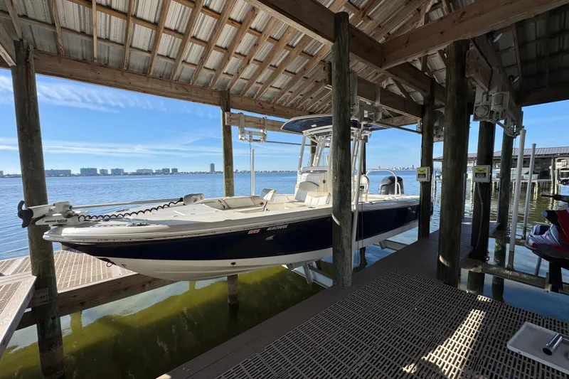 Slide: The Image of 2015 Robalo 246 Cayman boat docked under a wooden shelter by the water. - 6