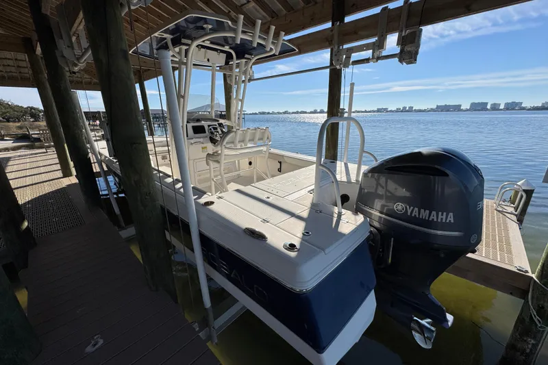 Slide: The Image of 2015 Robalo 246 Cayman boat docked with Yamaha engine, under a wooden shelter. - 7
