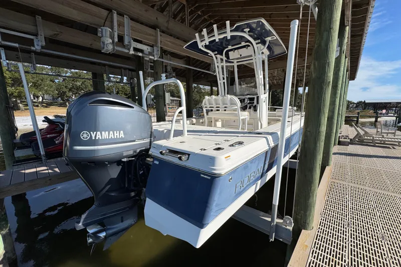 Slide: The Image of 2015 Robalo 246 Cayman boat with Yamaha engine docked under a wooden shelter. - 9