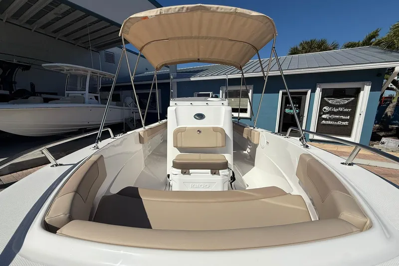 Slide: The Image of 2026 Edgewater 188CC boat with beige seating and canopy, docked near a blue building. - 10