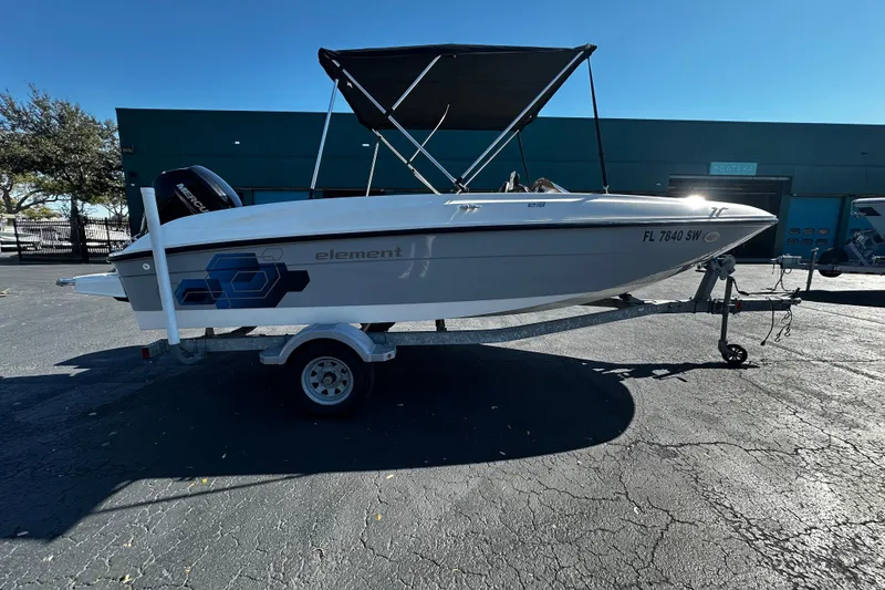 The Image of 2021 Bayliner Element E18 boat on trailer with canopy, parked outdoors. - 1