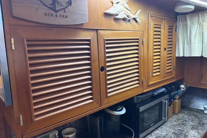 Slide: The Image of Wooden cabinets in a 1986 Ponderosa 42' boat kitchen with appliances and decor. - 16