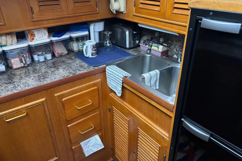 Slide: The Image of Compact kitchen area in a 1986 Ponderosa 42' boat with wooden cabinets and stainless steel sink. - 17