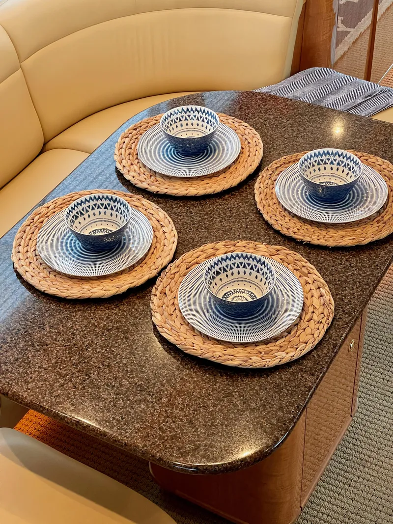 Slide: The Image of Elegant dining setup on 2002 Bayliner 5788 yacht with woven placemats and blue patterned dishes. - 13