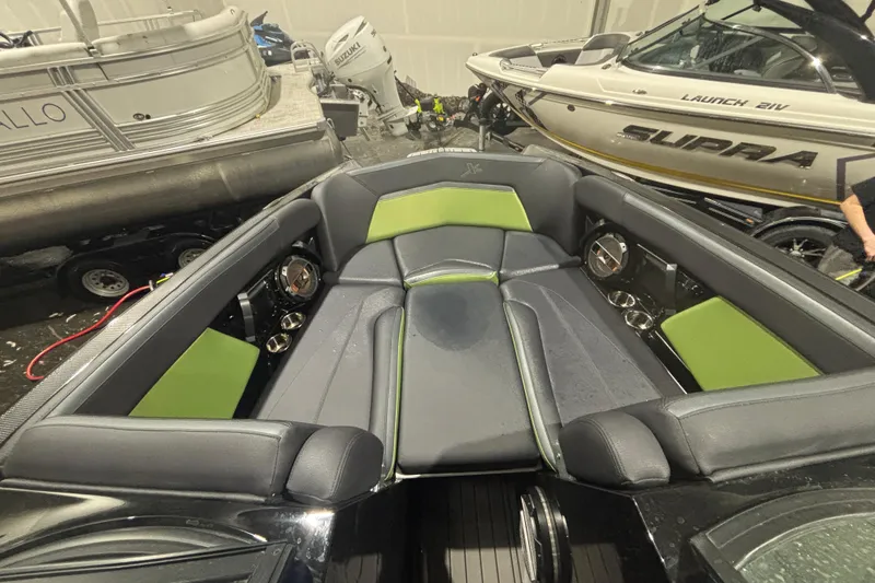 Slide: The Image of 2022 MasterCraft XStar boat interior with green and black seating, surrounded by other boats. - 12