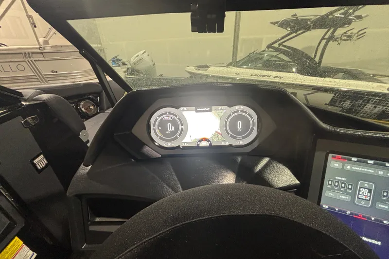 Slide: The Image of 2022 MasterCraft XStar dashboard with digital display and controls in a boat showroom. - 13