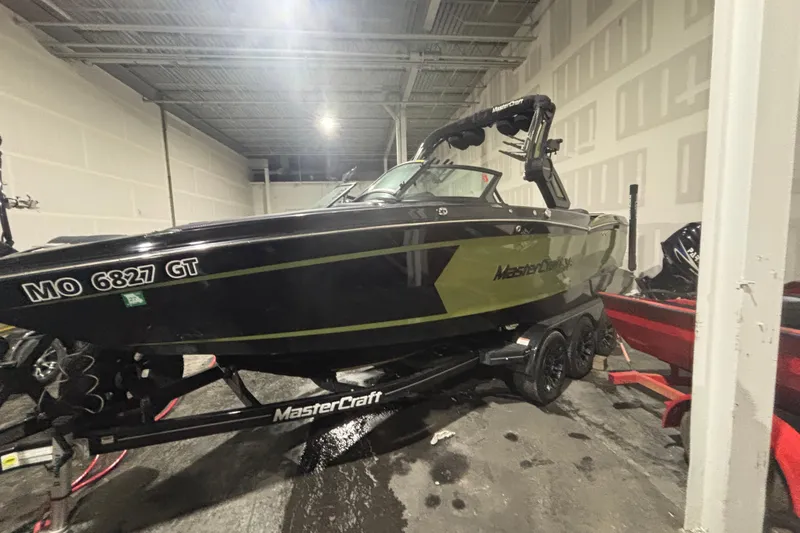 Slide: The Image of 2022 MasterCraft XStar boat in a garage, black and green design, on a trailer. - 4