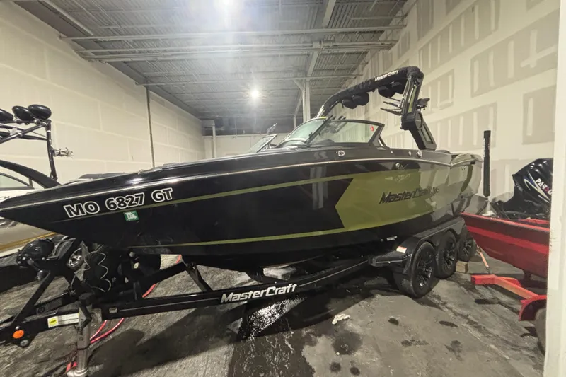 Slide: The Image of 2022 MasterCraft XStar boat in a garage, black and green design, on a trailer. - 5