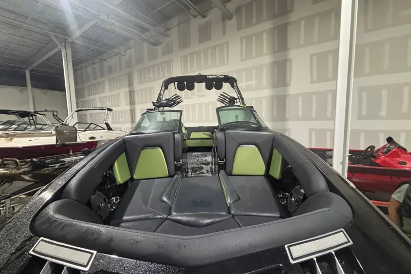 Slide: The Image of 2022 MasterCraft XStar boat interior with black and green seating in a showroom. - 6