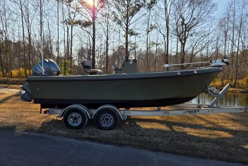 The Image of 2014 May-Craft 2000CC boat on trailer, parked near a wooded area. - 0