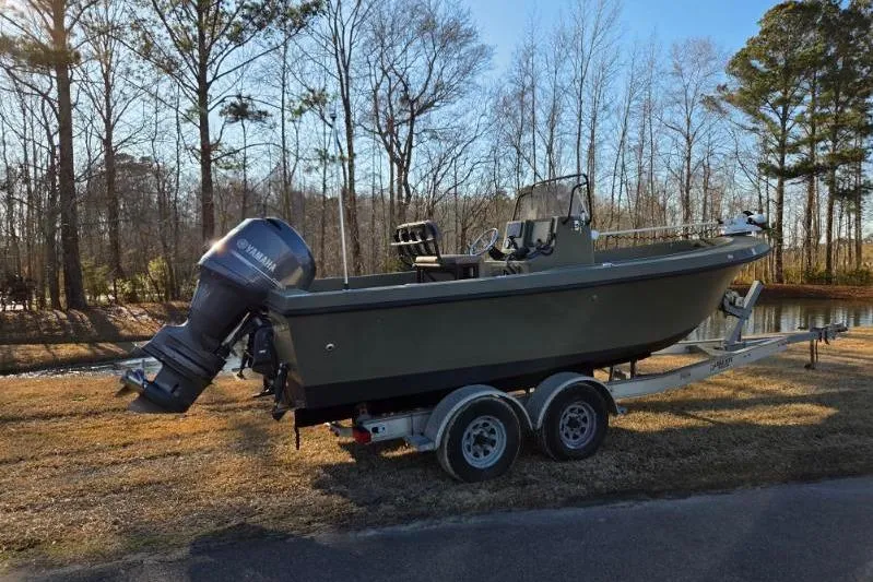 Slide: The Image of 2014 May-Craft 2000CC boat on trailer, parked near a wooded area. - 2