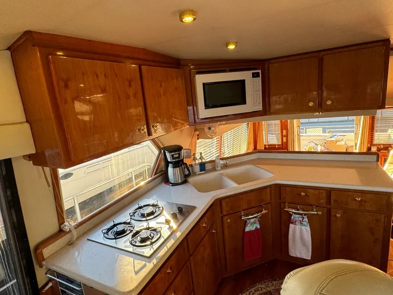 Slide: The Image of 2002 Navigator 5700 Rival yacht kitchen with stove, microwave, and wooden cabinets. - 43