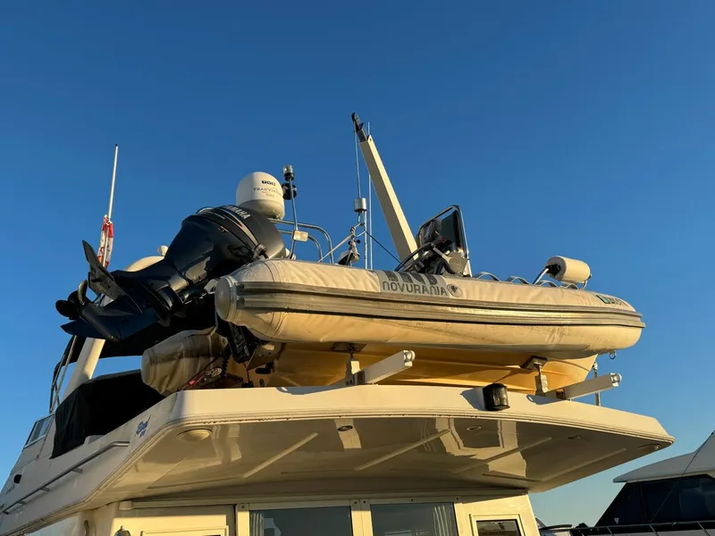 Slide: The Image of 2002 Navigator 5700 Rival yacht with inflatable boat on deck, under clear blue sky. - 5