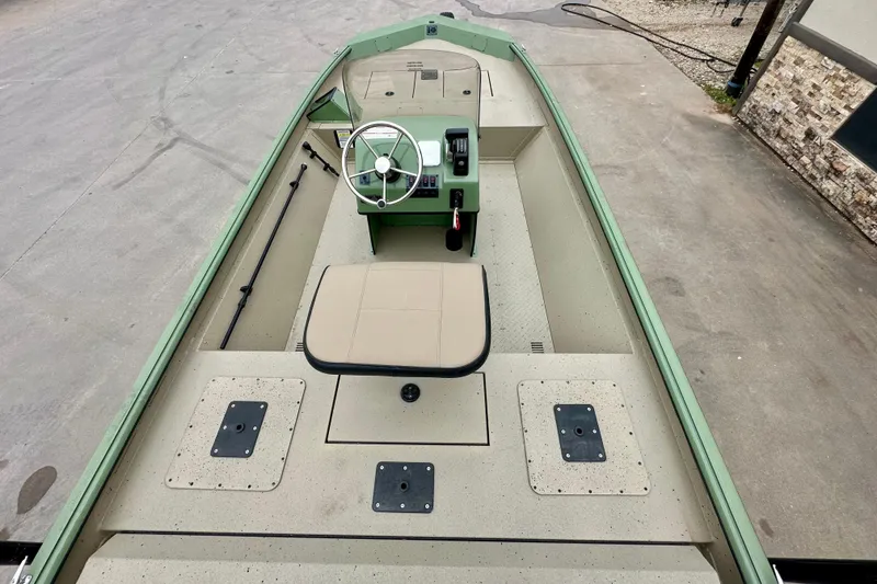 Slide: The Image of 2026 SeaArk Shadow 18 boat interior with steering wheel and seating, docked on concrete. - 19