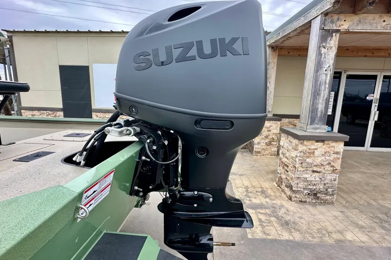 Slide: The Image of 2026 SeaArk Shadow 18 with Suzuki outboard motor, parked near a rustic building. - 6