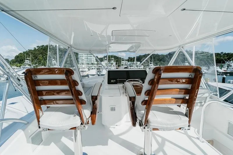 Slide: The Image of 2021 Viking 58 Convertible yacht helm with wooden chairs and marina view. - 102