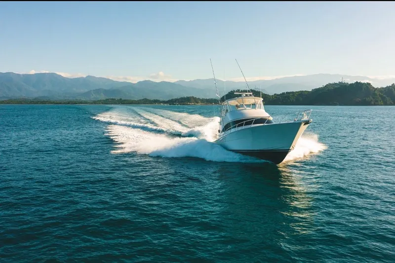 Slide: The Image of 2021 Viking 58 Convertible yacht cruising on open water with scenic mountain backdrop. - 3