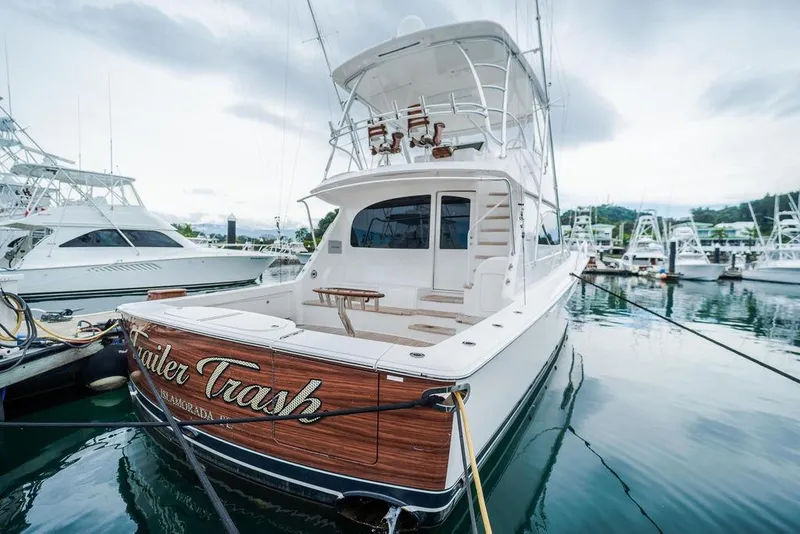 Slide: The Image of 2021 Viking 58 Convertible yacht docked in marina, rear view with name "Trailer Trash." - 37