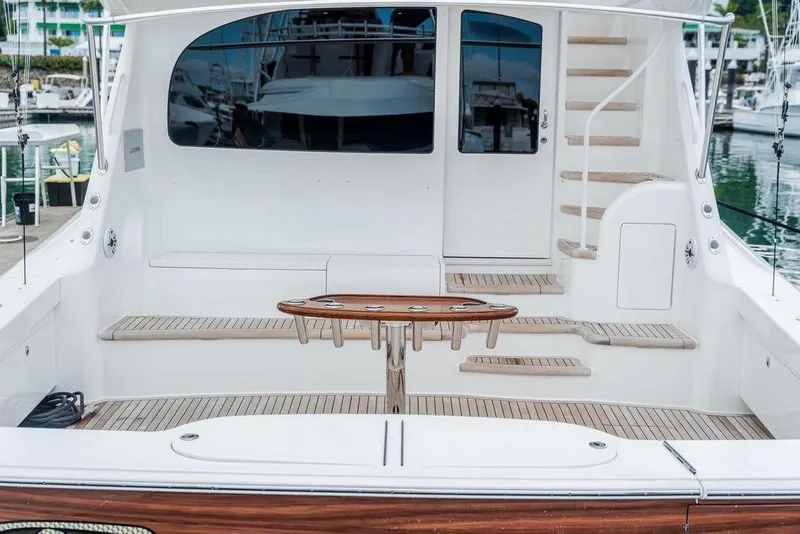 Slide: The Image of 2021 Viking 58 Convertible yacht cockpit with wooden table and steps, docked at marina. - 38