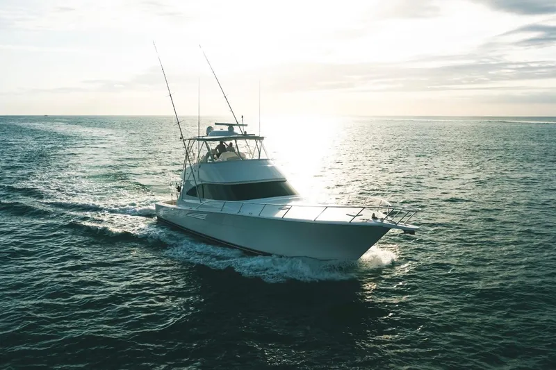 Slide: The Image of 2021 Viking 58 Convertible yacht cruising on open water at sunset. - 5