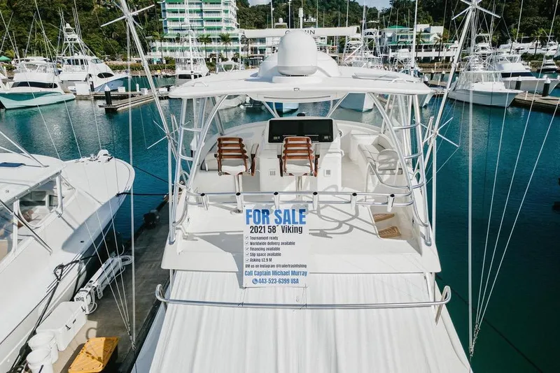 Slide: The Image of 2021 Viking 58 Convertible yacht for sale at marina, featuring spacious deck and seating. - 54