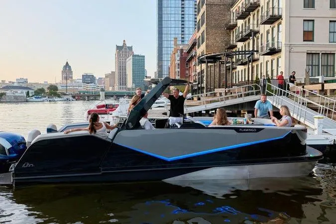Slide: The Image of Custom rOve 265 boat docked by urban waterfront, people socializing onboard, city skyline in background. - 13