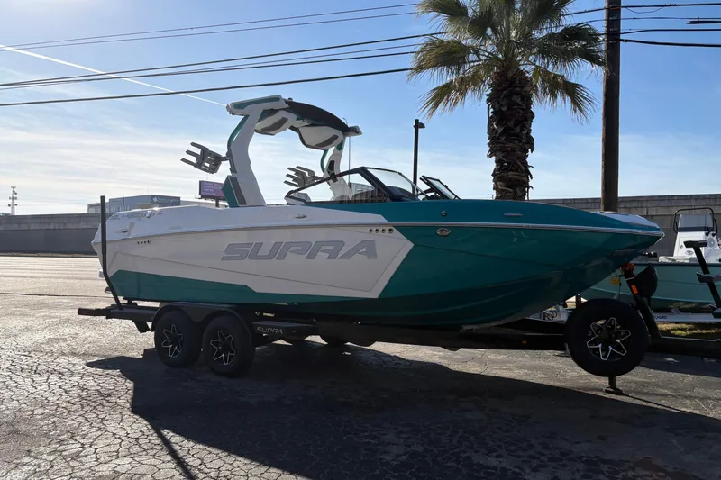 The Image of 2026 Supra SL 450 boat on trailer, parked outdoors under a clear sky. - 1