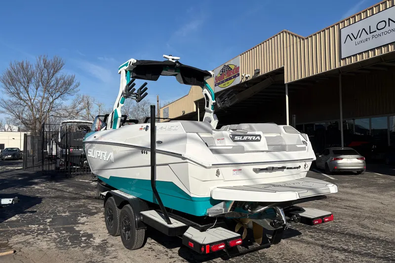 Slide: The Image of 2026 Supra SL 450 boat on trailer outside Avalon Luxury Pontoon dealership. - 6