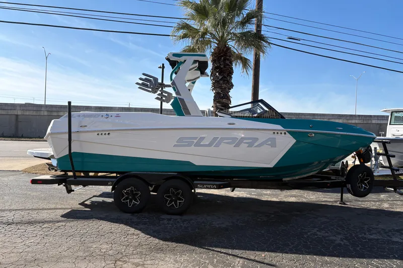 Slide: The Image of 2026 Supra SL 450 boat on trailer, parked outdoors under clear blue sky. - 62