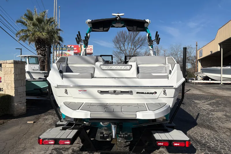 Slide: The Image of 2026 Supra SL 450 boat rear view, parked outdoors on a sunny day. - 7