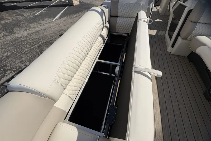 Slide: The Image of 2026 Avalon Exalibur LTD 27 Elite Winshield boat interior with beige seating and storage compartment. - 13