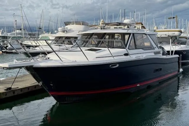 The Image of 2026 Cutwater C-288 Coupe boat docked in a marina, surrounded by other vessels. - 0