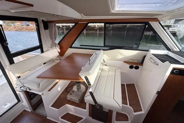 Slide: The Image of Interior of 2026 Cutwater C-288 Coupe, featuring elegant seating and wooden table by large windows. - 8