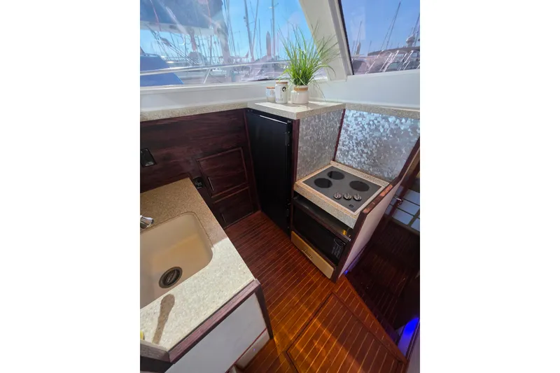 Slide: The Image of Compact kitchen in 1990 Novatec 44 Aft Cockpit Motor Yacht with stove, sink, and wood flooring. - 19