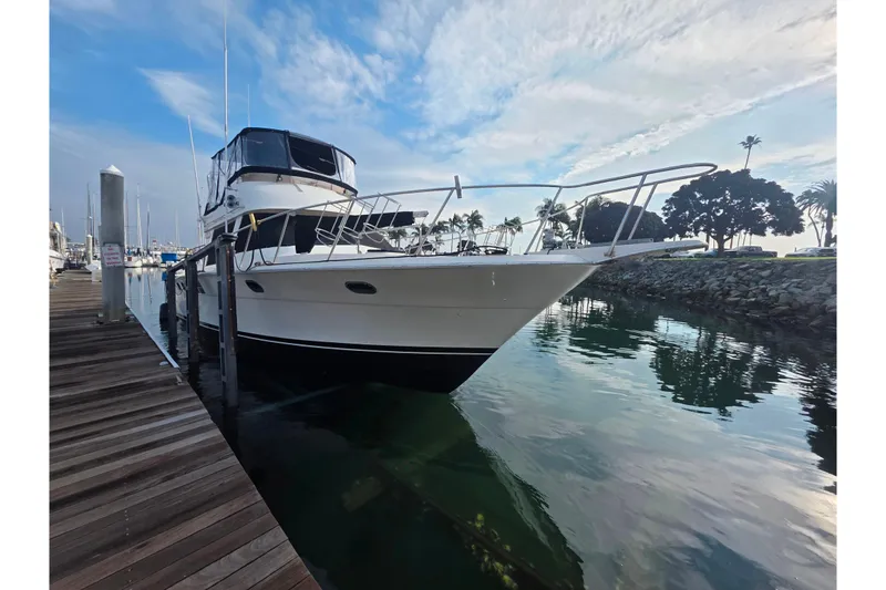 Slide: The Image of 1988 Novatec yacht docked at marina, reflecting on calm water under a partly cloudy sky. - 4