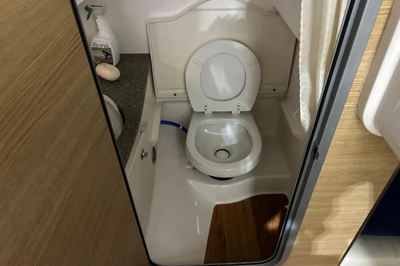 Slide: The Image of 2012 Chaparral 327 SSX boat bathroom with toilet and cleaning supplies. - 34