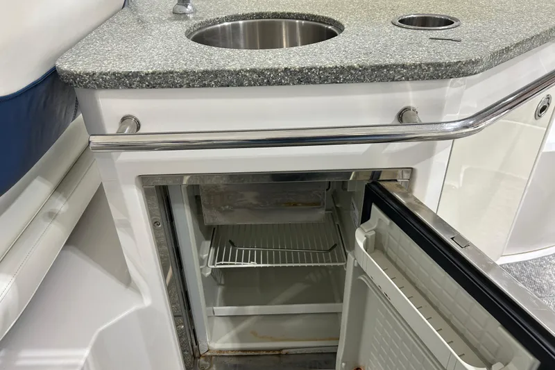 Slide: The Image of 2012 Chaparral 327 SSX boat kitchenette with open mini fridge and sink. - 86