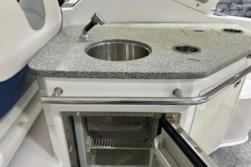 Slide: The Image of 2012 Chaparral 327 SSX boat kitchenette with sink, countertop, and open mini-fridge. - 87