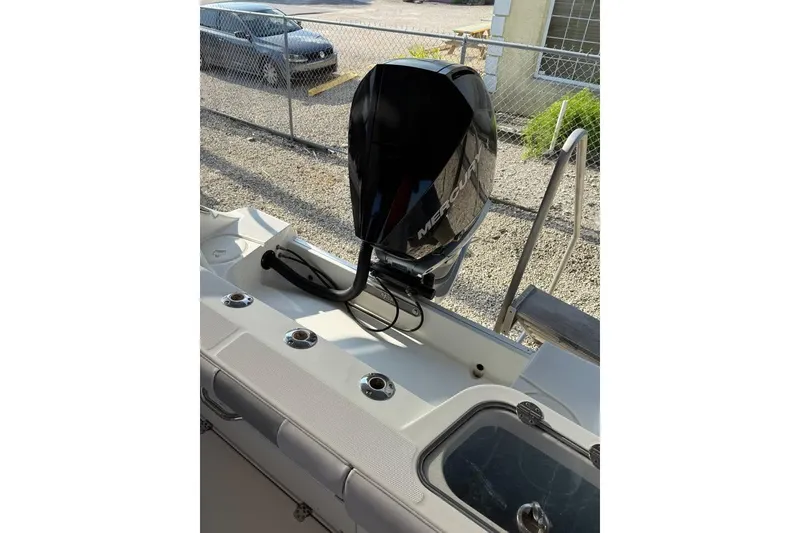 Slide: The Image of 2021 Mako 234 Center Console boat with Mercury outboard motor, docked near a fence. - 13