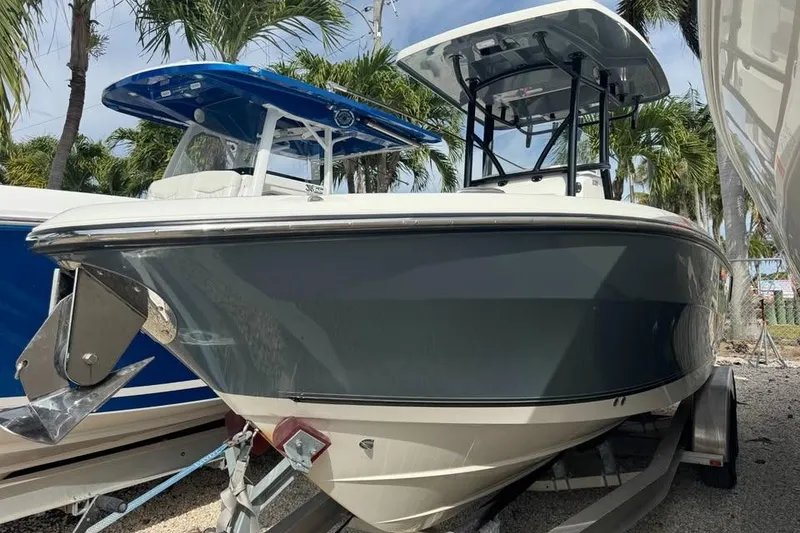 The Image of 2021 Mako 234 Center Console boat on trailer, surrounded by palm trees. - 2